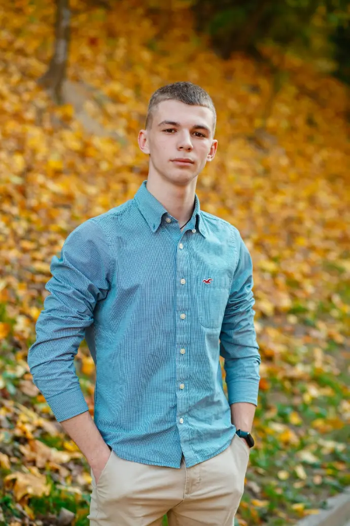man in blue dress shirt standing near brown leaves during daytime